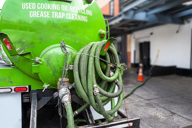 a technician pumping a grease trap in a commercial building in Cedar Valley